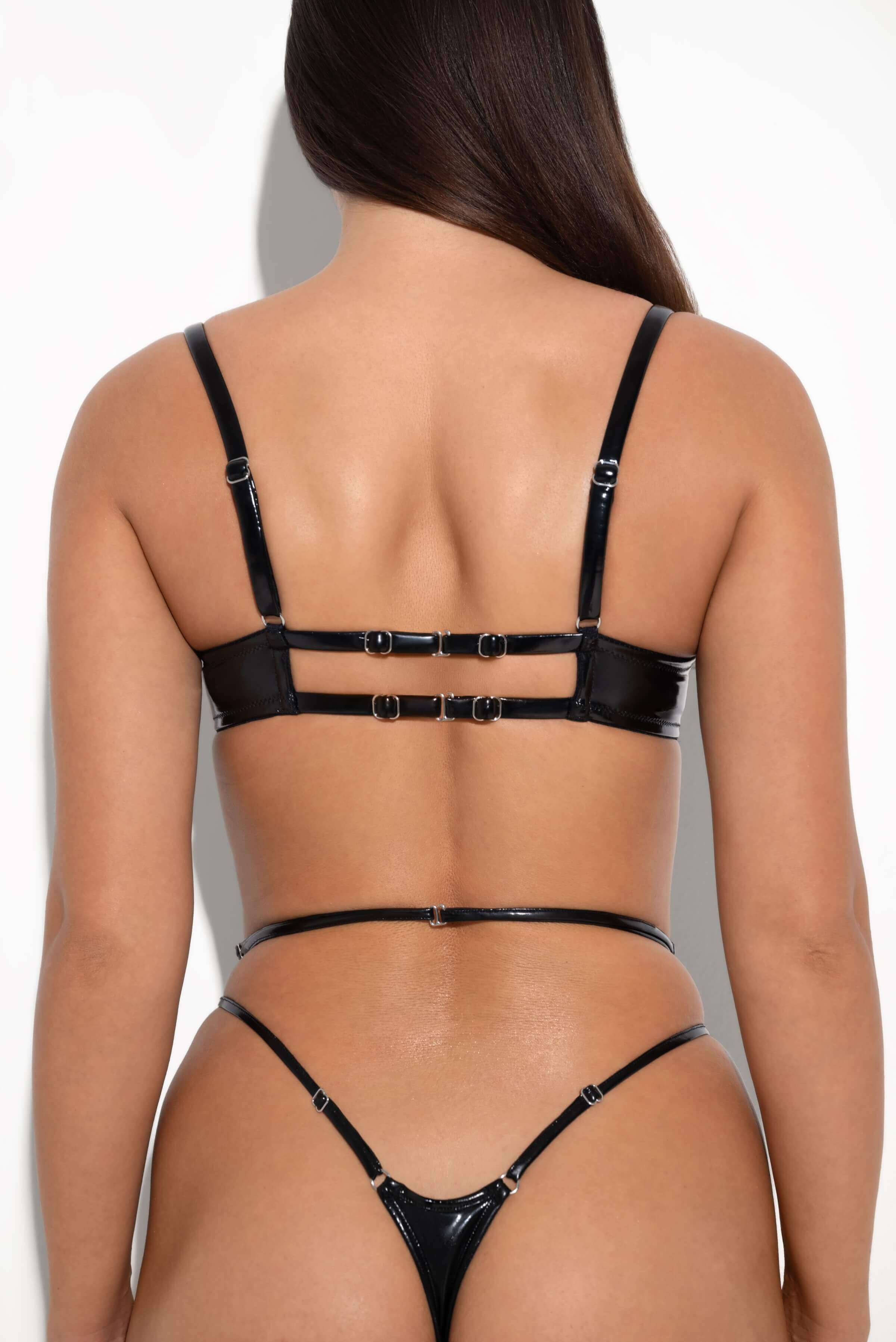 Back view of black patent vinyl strappy bra with double buckle closure and matching thong set.